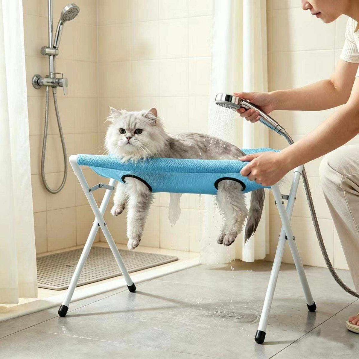 Foldable Pet Bathing Stand with a blue fabric hammock, white metal legs, and a fluffy cat supported during bathing