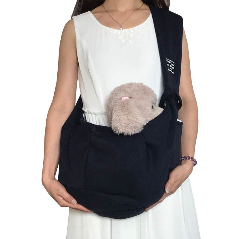 Pet Dog Travel Sling in black soft fabric with a wide shoulder strap, front pocket and plush dog peeking out