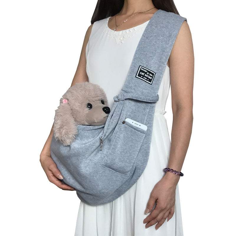 Pet Dog Travel Sling in soft gray fabric with a wide shoulder strap, front phone pocket, and small dog peeking out